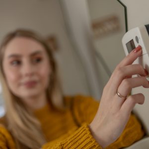 image of a woman setting up the thermostat